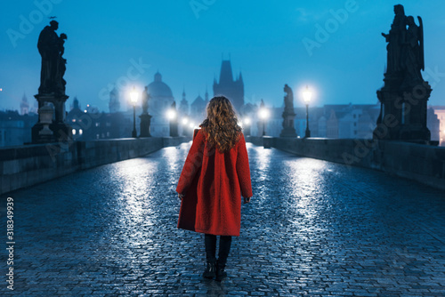 Fototapete Female tourist walking alone on the Charles Bridge during the early morning in P