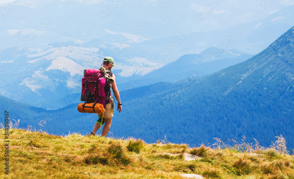 Hiker with big backpack on blue mountains background_