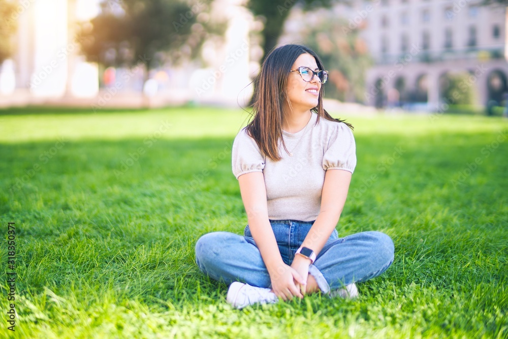 Young beautiful woman smiling happy and confident. Sitting on the grass with smile on face at park Young beautiful woman smiling happy and confident. Sitting on the grass with smile on face at park