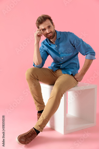 young casual man smiling and holding hand to temple