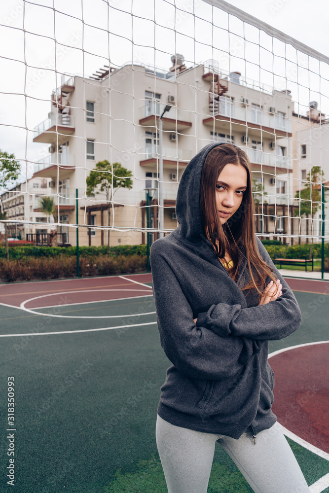 Fototapeta premium a girl with a carefully serious look stands arms crossed on her chest on a sports court