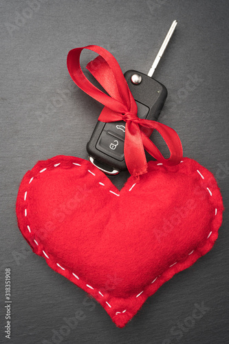Obraz na płótnie Car key with red bow and a heart on dark black slate plate background. Christmas or Valentine's Day gift or present abstract concept. Vertical orientation. Flat lay top view. w salonie
