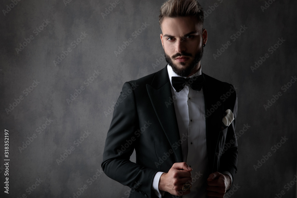 businessman standing and fixing jacket while looking at camera businessman standing and fixing jacket while looking at camera