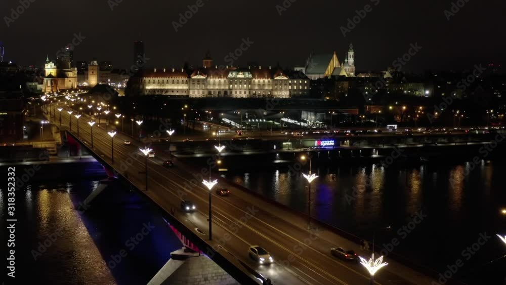 Drone shot on a night bridge with illumination in the historical part of Warsaw. Aerial view of the bridge in the old city, panoramic view of the royal palace and the trafficway on the bridge. Drone shot on a night bridge with illumination in the historical part of Warsaw. Aerial view of the bridge in the old city, panoramic view of the royal palace and the trafficway on the bridge.