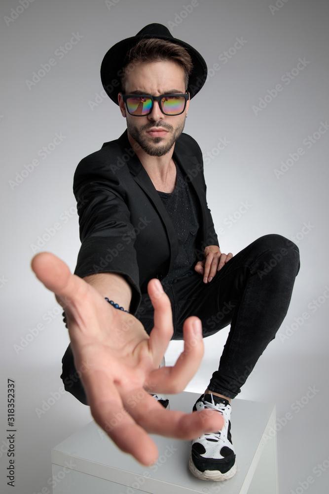Foto Stock cool young guy holding hand close to the camera in a fashion pose  | Adobe Stock