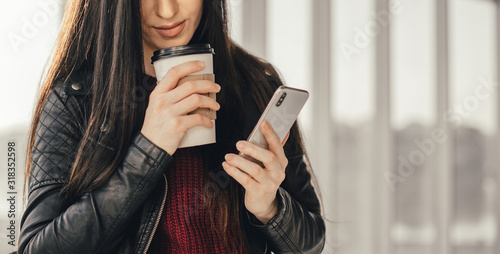 Young pretty woman waitin for friend with cup of coffee and talking by phone photo