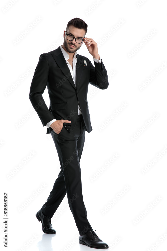 formal businessman walking with hand in pocket fixing glasses formal businessman walking with hand in pocket fixing glasses