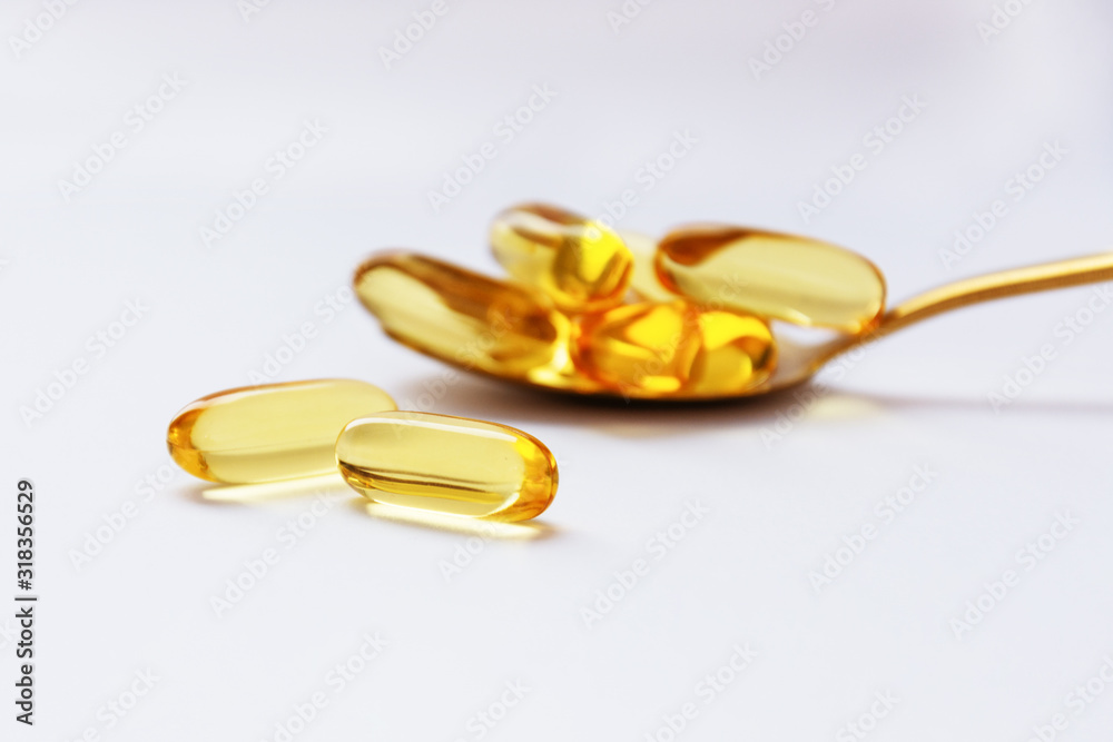 Cod liver oil omega 3 gel capsules on a spoon on white background. Cod liver oil omega 3 gel capsules on a spoon on white background.