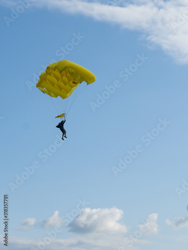 Parachuter descending with parachute against blue sky. Skydiver in the sky. People under parachute in the sky.