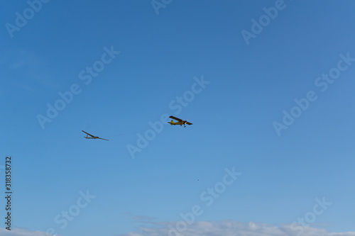Plane pulling glider. White clouds in background. Self propelled glider in air. Plane dragging the glider.