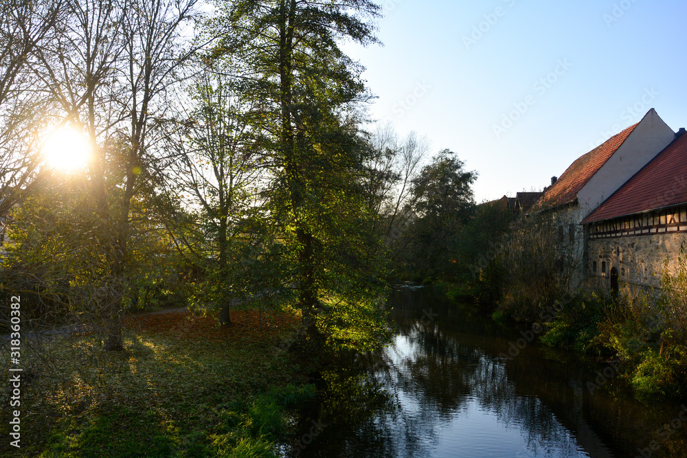 A stream with nature and old houses in the evening light with sun