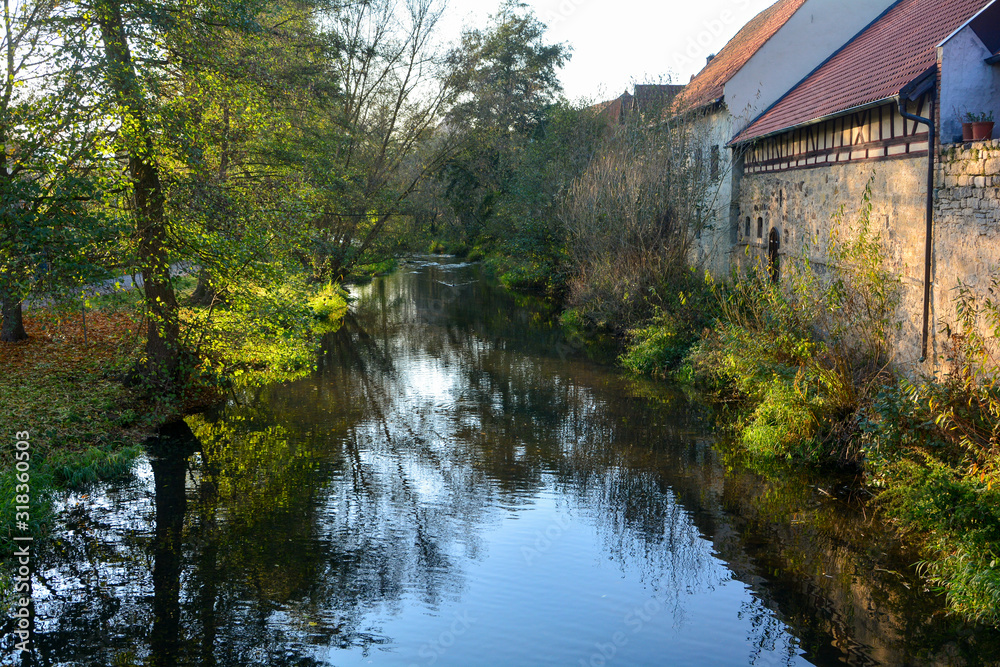 Creek with nature and old houses in the evening light,with reflection
