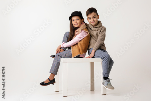 Cute stylish little couple child girl and boy in fashionable clothes sittting together at studio. kids fashion concept. © producer