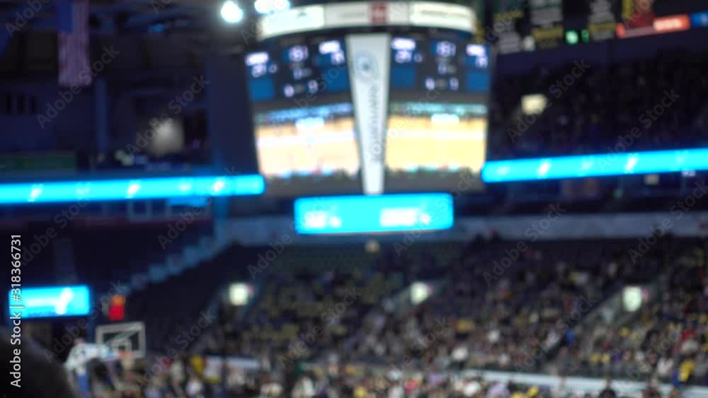 Jumbotron Slightly Right Of Center With People In Bleechers Cheering Team During Basketball Game Slightly Blurred