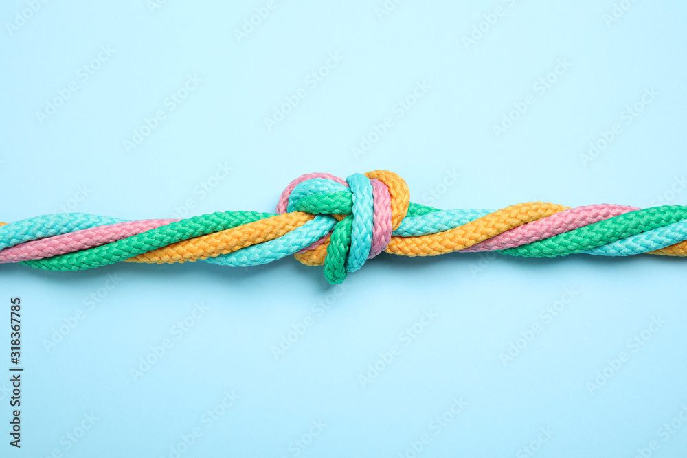 Colorful ropes tied together on light blue background, top view. Unity concept Colorful ropes tied together on light blue background, top view. Unity concept