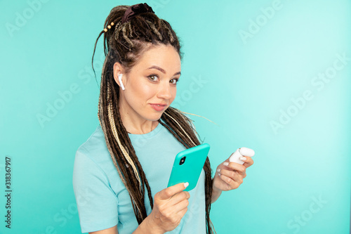 Listening music and talking phone with earphones. Young female person with airpods and phone photo
