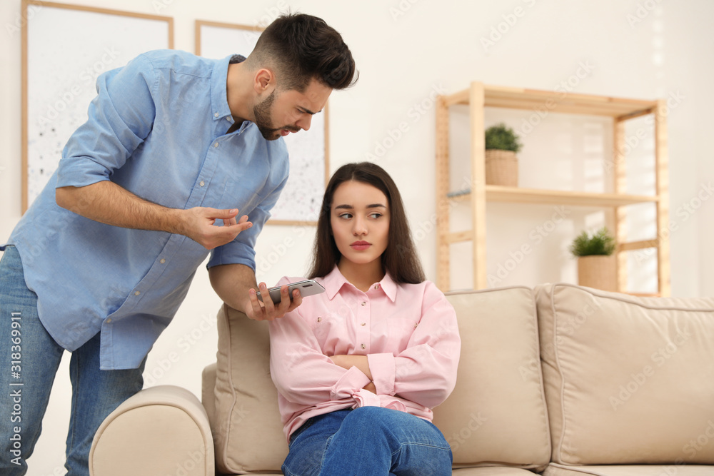 Young couple arguing about smartphone at home. Problems in relationship