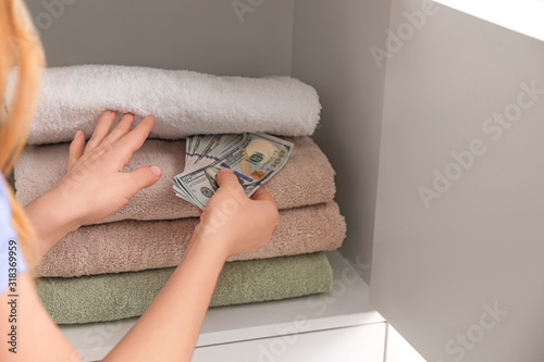 Woman hiding money between towels, closeup. Financial savings