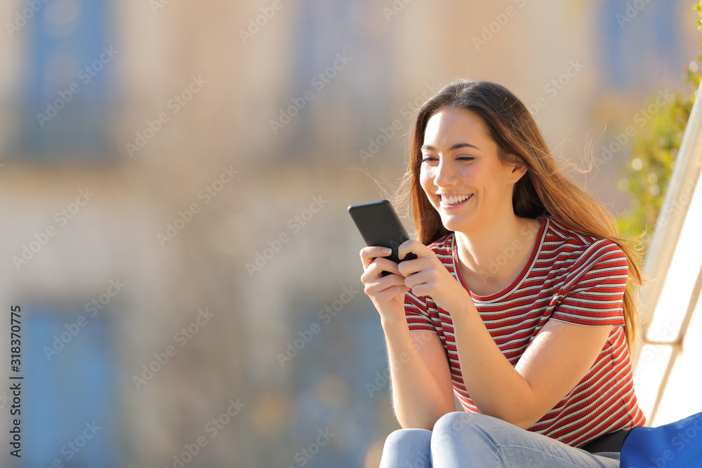 Happy student checking mobile phone in a campus Happy student checking mobile phone in a campus