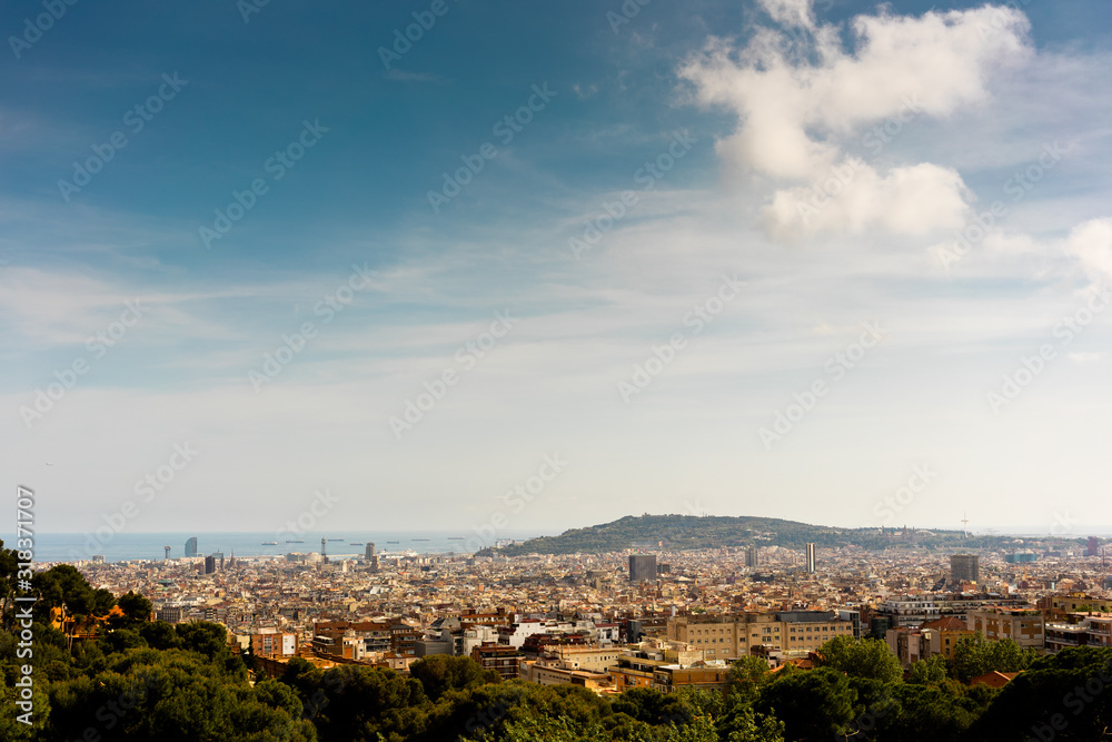 view of Barcelona and the sea from a vantage point in a park during sunset framed by trees