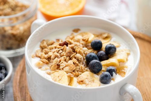 Granola with fruits and yogurt in white bowl closeup view. Healthy breakfast food