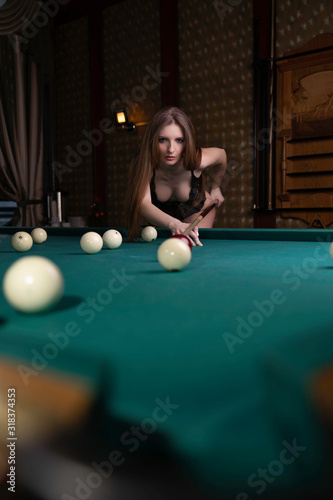 beautiful blonde girl in black lingerie plays billiards
