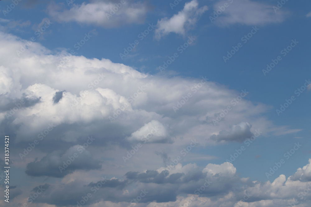The sun shines through the cumulus clouds in the blue sky. Background and texture for artists and design. Bright light in the eyes. Water in gaseous state. The circulation of fluid in nature The sun shines through the cumulus clouds in the blue sky. Background and texture for artists and design. Bright light in the eyes. Water in gaseous state. The circulation of fluid in nature