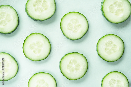 Pattern with freshly cut cucumber slices on green background
