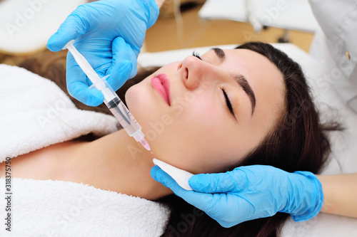 a cosmetic surgeon performs a facial skin rejuvenation procedure using an innovative technology in which plasma enriched with platelets is injected into the patient.