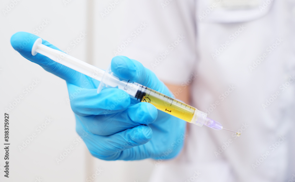 syringe with plasma in hand in a rubber glove close-up on a white background. syringe with plasma in hand in a rubber glove close-up on a white background.