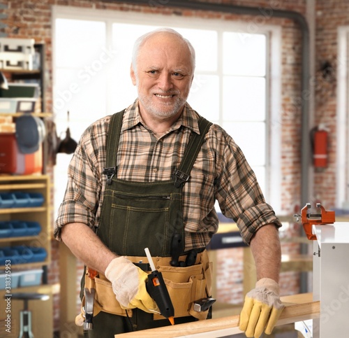 Senior happy handyman working at DIY workshop photo