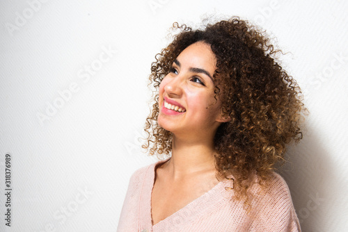 Close up side of happy young african American woman with curly hair against white wall