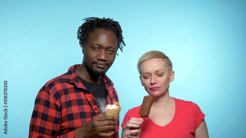 African man, Caucasian woman eating chocolate and cream ice cream. African man, Caucasian woman eating chocolate and cream ice cream.