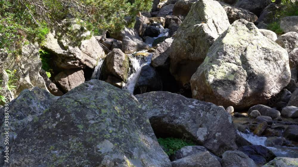 mountain stream with crystal clear water flows among huge stones in mountains
