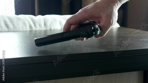 Man's hand takes the gun from the table and loads it photo