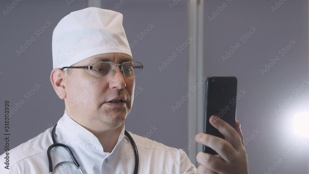 a doctor in uniform with a stethoscope talks to a patient in a video chat application, video conferencing, online patient consultation, remote medical consultation in an Internet application concept