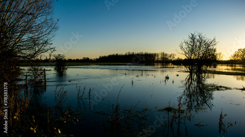 Flooded lands around Oxford area, Winter time floods in Chiselhampton in sunset, scenic view of rural lands with reflections in calm water, trees river and birds