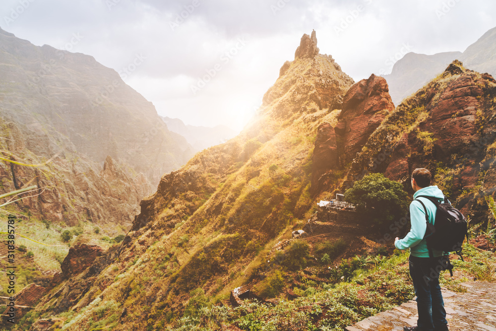 Santo Antao Island, Cape Verde. Traveler man with camera on sunset in front of mountain ridge and ravine on the cobbled path to Xo-Xo Valley