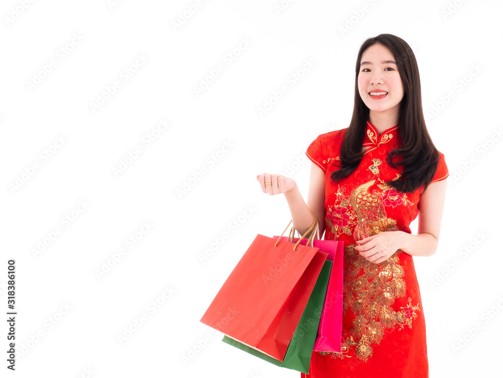 Asian young lady smile and enjoy to purchase in Chinese New Year festival promotion on sale event with holding shopping paper bag and wear qipao or cheongsam dress fashion on isolated white background Asian young lady smile and enjoy to purchase in Chinese New Year festival promotion on sale event with holding shopping paper bag and wear qipao or cheongsam dress fashion on isolated white background