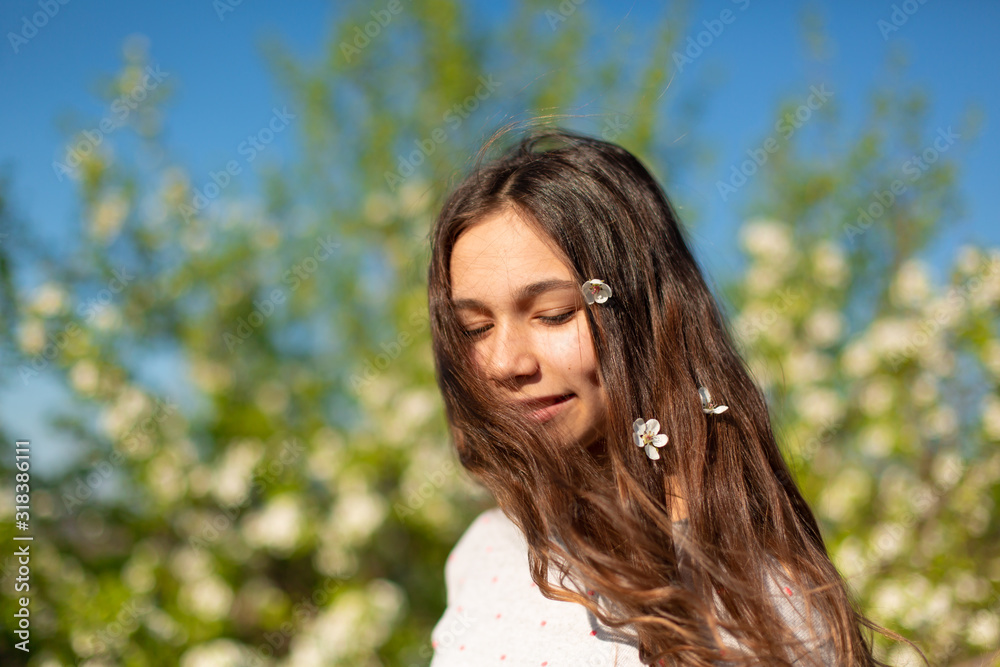 Portrait of a young beautiful teenager girl in a blooming spring green garden Portrait of a young beautiful teenager girl in a blooming spring green garden