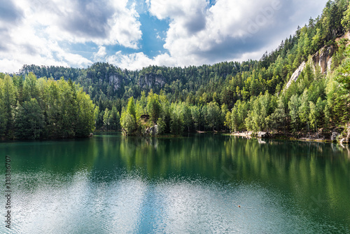 Green water of calm forest lake between small mountains covered with forest