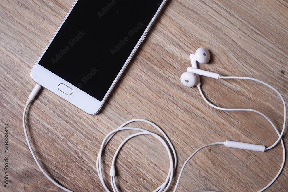 Mobile phone and earphones on wooden background Mobile phone and earphones on wooden background