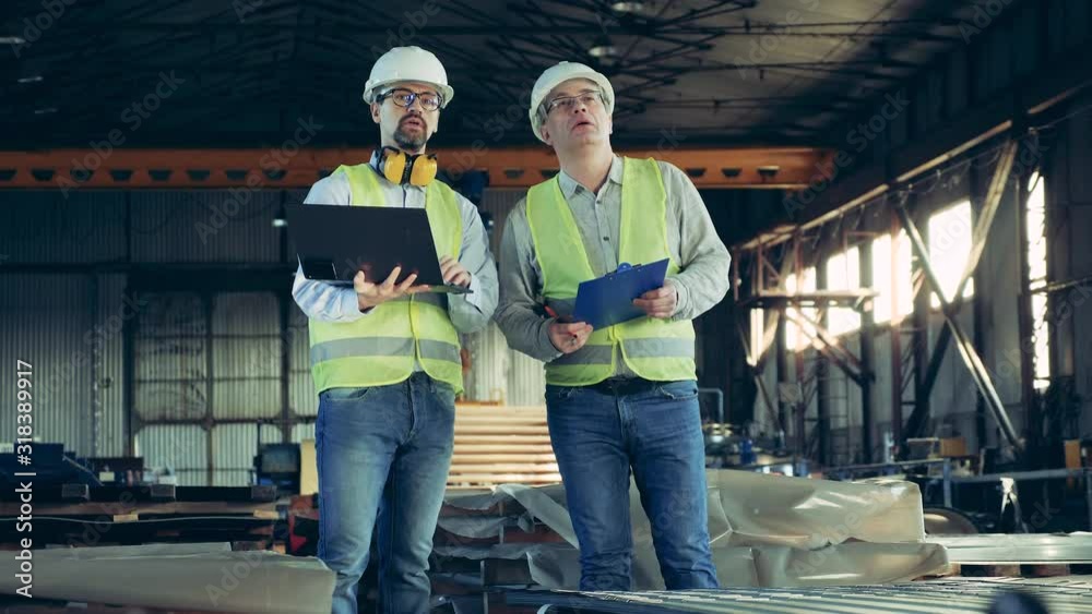Metalware factory unit with male technicians inspecting it Metalware factory unit with male technicians inspecting it