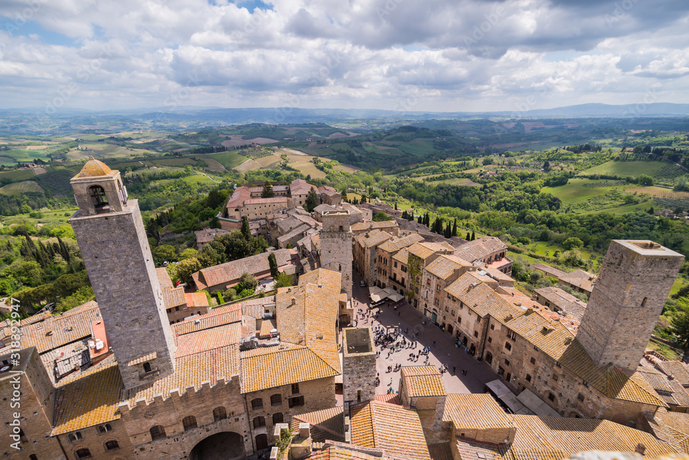 cityscape panoramic of san gimignano with small town brick houses and tower torre grossa big tower and piazza cisterna with water well in tuscany in italy sky with clouds