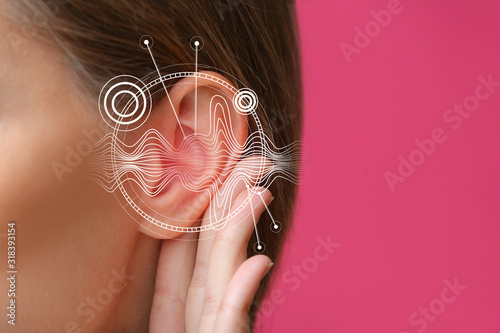Young woman with hearing problem on color background, closeup photo