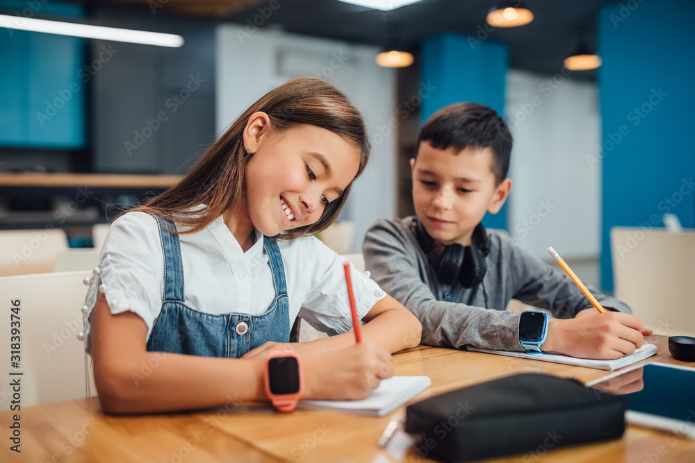 Two kids writing homework at modern blue classroom. Two kids writing homework at modern blue classroom.