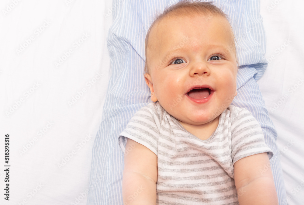 Happy laughing face portrait of 6 month old baby with open mouth close-up