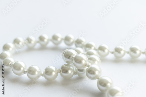 White pearls necklace on white background, clean and tidy picture, shiny pearl, close view and lots of negative space