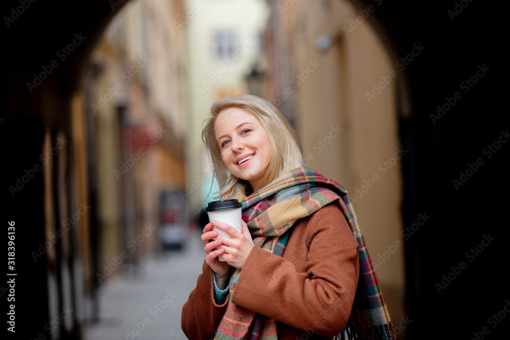 Blonde woman with cup of coffee in old town