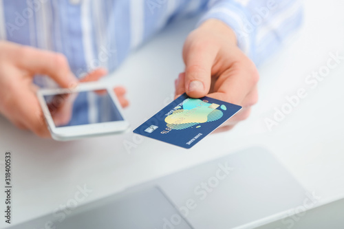 Woman with laptop, mobile phone and credit card at table, closeup